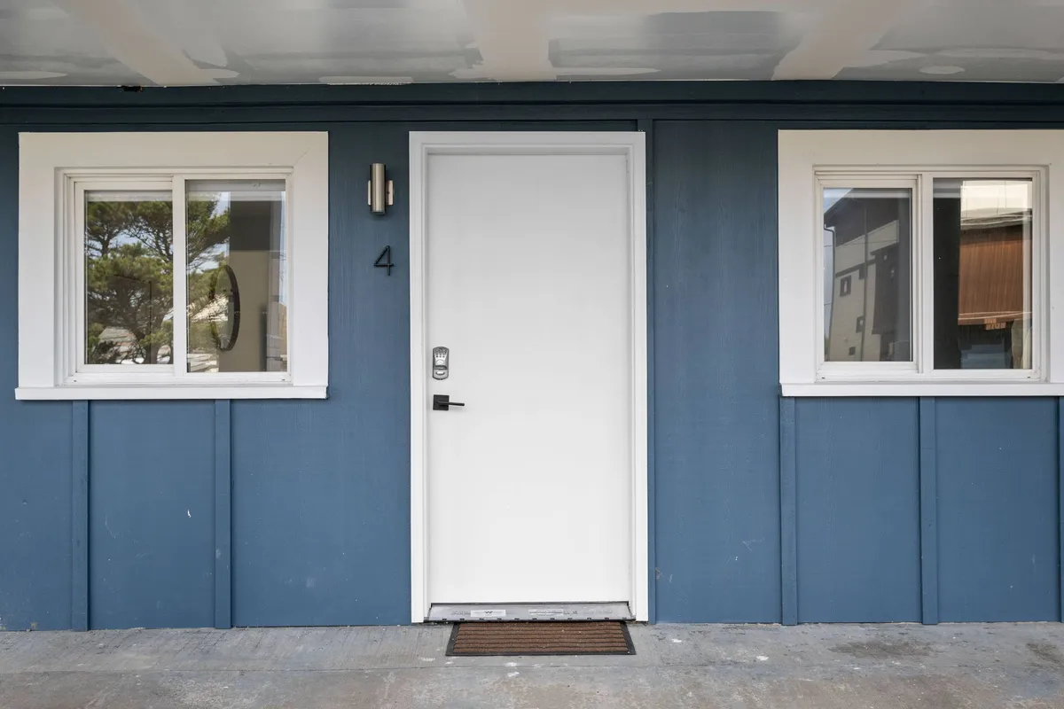 A welcoming exterior view of the inn’s entry, complete with a white door, blue siding, and windows. The entrance appears accessible and inviting, perfect for easy comings and goings with a pet.